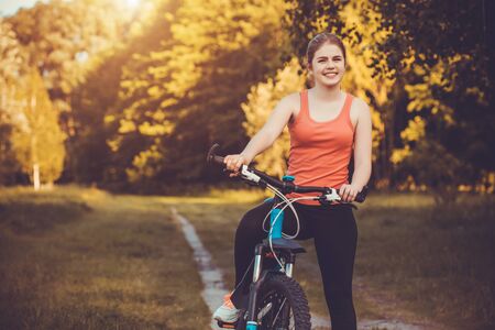 Happy woman cyclist rides in the forest on a mountain bike. Adventure travel. wide angleの写真素材