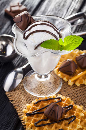 Ice Cream with chocolate candies, Mint and waffles. Homemade Organic product. On the black wooden table.の写真素材