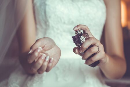 Bride's hands holding a bottle with parfumes. Close upの写真素材