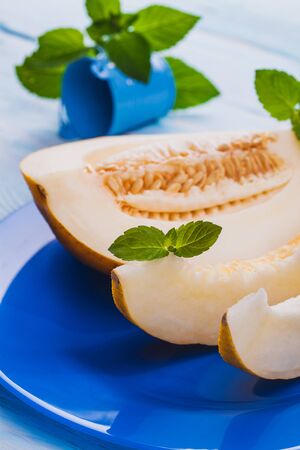 Fresh sweet orange melon in blue plate on the white wooden tableの写真素材