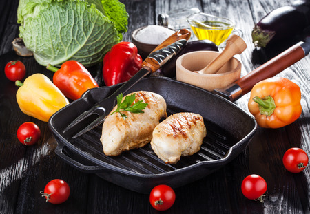 Tasty Grilled chicken fillet and bell pepper on a pap on the black wooden table.の写真素材