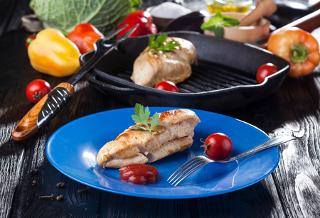 Tasty Grilled chicken fillet and bell pepper on a plate on the black wooden table.の写真素材