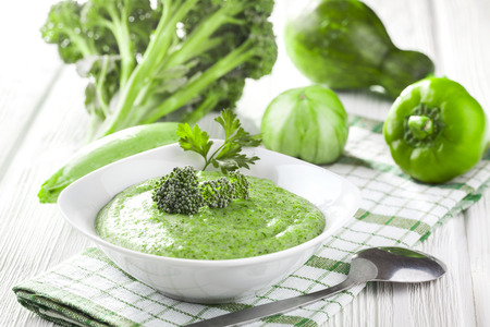 Broccoli cream soup with fresh vegetables on the white wooden tableの写真素材