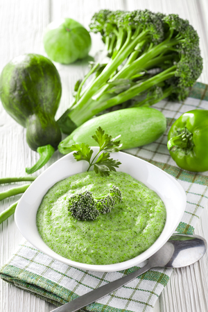 Broccoli cream soup with fresh vegetables on the white wooden tableの写真素材