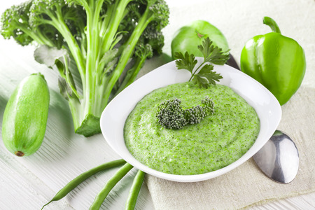 Broccoli cream soup with fresh vegetables on the white wooden tableの写真素材