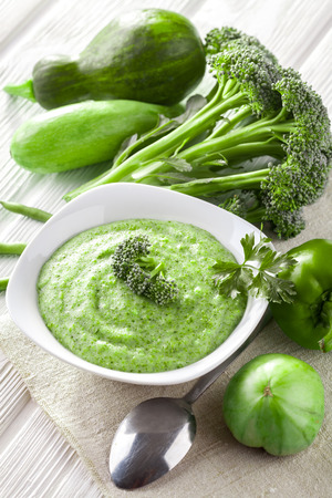Broccoli cream soup with fresh vegetables on the white wooden tableの写真素材