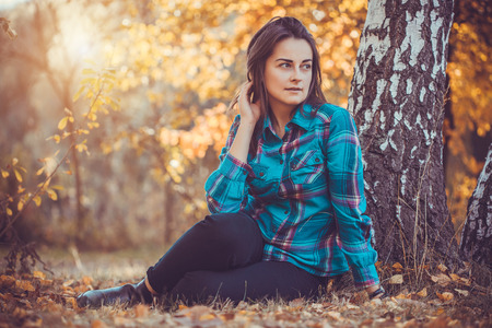 Portrait of a beautiful girl with long black hair in the autumn parkの写真素材