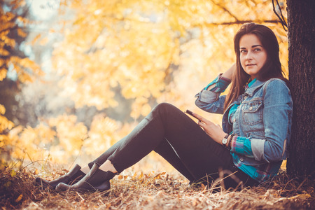 Portrait of a beautiful girl with long black hair in the autumn parkの写真素材