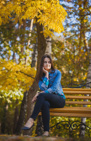 Portrait of a beautiful girl with long black hair in the autumn parkの写真素材