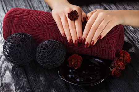 beautiful red manicure with rose flowers on the black wooden tableの写真素材