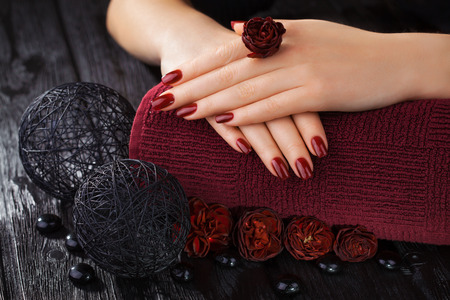 beautiful red manicure with roses and towel on the black wooden tableの写真素材