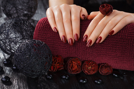 beautiful red manicure with roses and towel on the black wooden tableの写真素材
