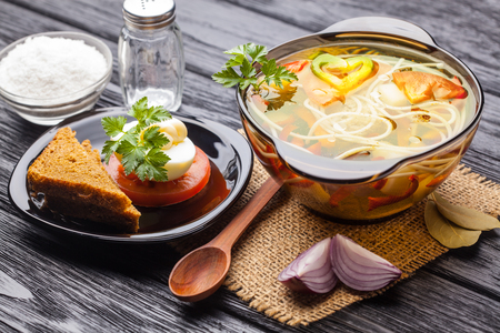 Fresh vegetable soup with noodles in a pot on the black wooden backgroundの写真素材