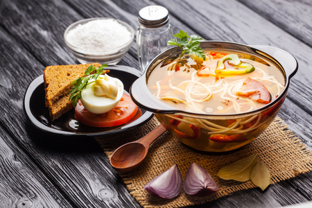 Fresh vegetable soup with noodles in a pot on the black wooden backgroundの写真素材