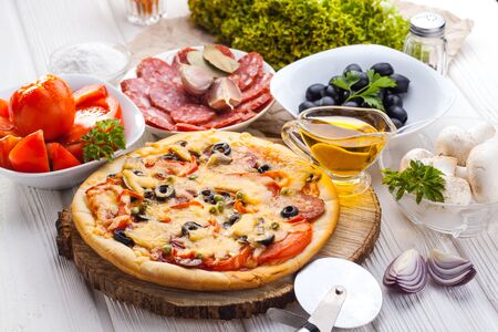 Delicious italian pizza and ingredients served on the white wooden tableの写真素材
