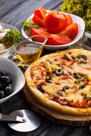Delicious Homemade pizza and ingredients served on the black wooden tableの写真素材