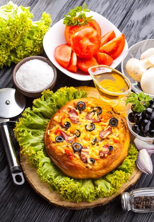 Delicious Homemade pizza and ingredients served on the black wooden tableの写真素材