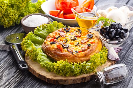 Delicious Homemade pizza and ingredients served on the black wooden tableの写真素材