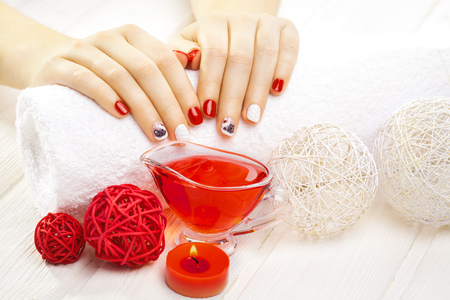 beautiful red manicure with dekor and towel on the white wooden table. spaの写真素材
