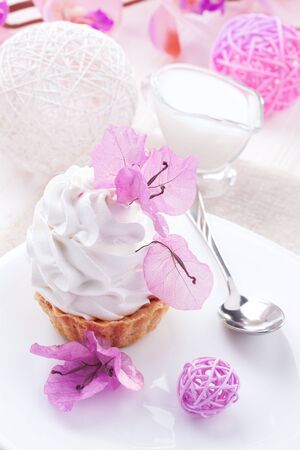 homemade White cake with cream protein with the decor of pink flowers on a wooden tableの写真素材