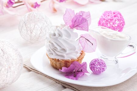 homemade White cake with cream protein with the decor of pink flowers on a wooden tableの写真素材