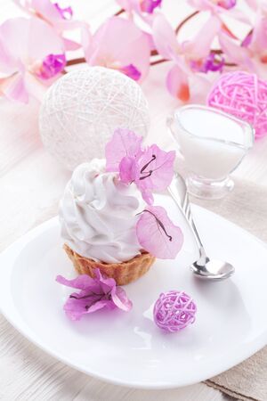 homemade White cake with cream protein with the decor of pink flowers on a wooden tableの写真素材