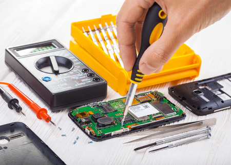 repair and testing smartphone with a multimeter on a white tableの写真素材