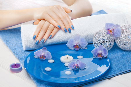 beautiful blue manicure with orchid and towel on the white wooden table. spaの写真素材