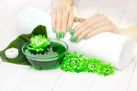 beautiful green manicure with chrysanthemum and towel on the white wooden table. spaの写真素材