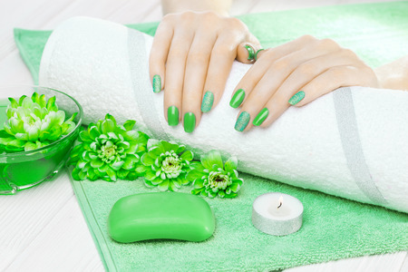 beautiful green manicure with oil and candles, chrysanthemum and towel on the white wooden table. spaの写真素材