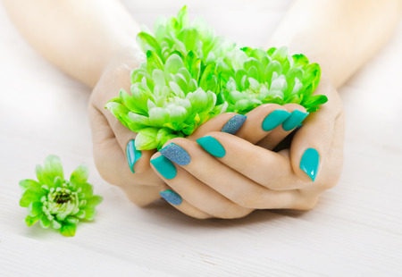 beautiful turquoise manicure with oil and candles, chrysanthemum and towel on the white wooden table. spaの写真素材