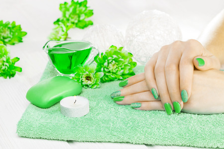 beautiful green manicure with oil and candles, chrysanthemum and towel on the white wooden table. spaの写真素材