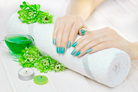 beautiful turquoise manicure with chrysanthemum and towel on the white wooden table. spaの写真素材