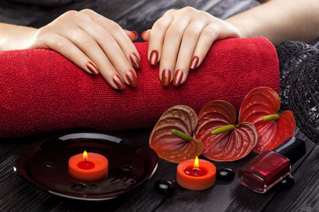 beautiful red manicure with red calla flower and towel on the black wooden table.の写真素材