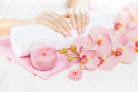 beautiful pink manicure with orchid, candle and towel on the white wooden table.の写真素材