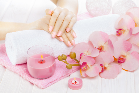 beautiful pink manicure with decor, orchid, towel and candle on the white wooden table. spaの写真素材