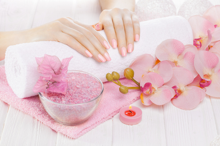 beautiful pink manicure with decor, orchid, towel and candle on the white wooden table. spaの写真素材