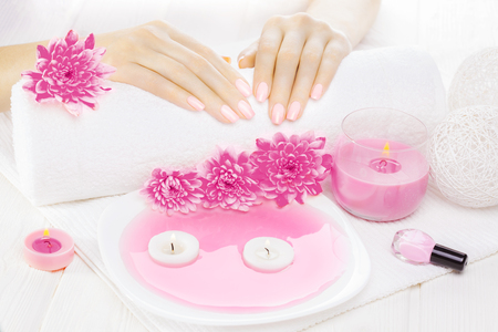 beautiful pink manicure with oil and candles, chrysanthemum and towel on the white wooden table. spaの写真素材