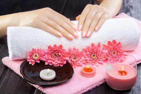 beautiful pink manicure with chrysanthemum and towel on the black wooden table. spaの写真素材