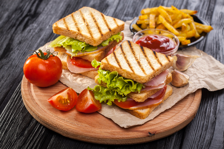 club sandwich with Tomato, lettuce, bacon, ham and french fries on the black wooden tableの写真素材