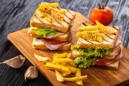 club sandwich with Tomato, lettuce, bacon, ham and french fries on the black wooden tableの写真素材