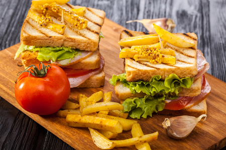 club sandwich with Tomato, lettuce, bacon, ham and french fries on the black wooden tableの写真素材