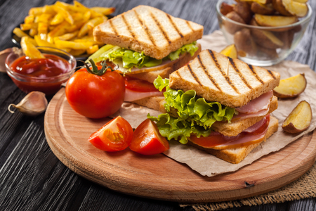 club sandwich with Tomato, lettuce, bacon, ham and french fries on the black wooden tableの写真素材