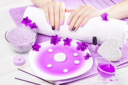 beautiful purple manicure with violet, candle and towel on the white wooden table. spaの写真素材
