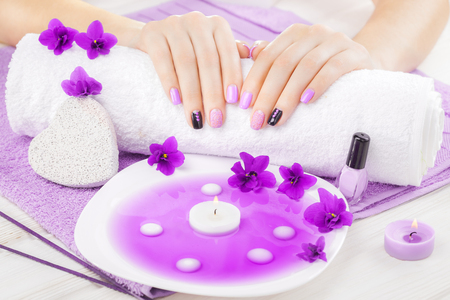 beautiful purple manicure with violet, candle and towel on the white wooden table. spaの写真素材