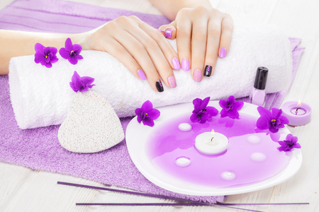 beautiful purple manicure with violet, candle and towel on the white wooden table. spaの写真素材