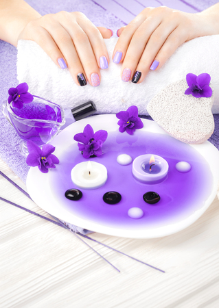 beautiful purple manicure with violet, candle and towel on the white wooden table. spaの写真素材