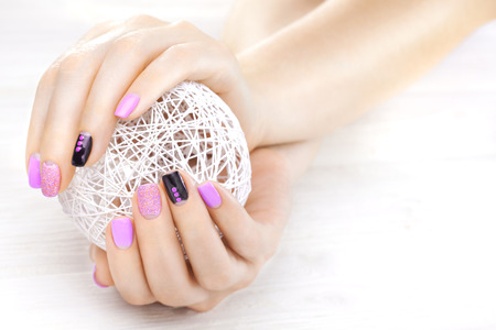 purple manicure with a white ball of yarnの写真素材