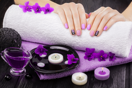 beautiful purple manicure with violet, candle and towel on the black wooden table. spaの写真素材