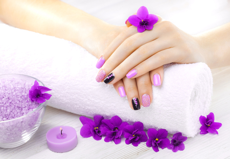beautiful purple manicure with violet, candle and towel on the white wooden table. spaの写真素材